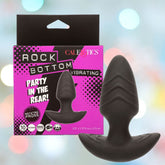 The CalExotics Rock Bottom Rotating Probe Vibrating Butt Plug, made of body-safe silicone in black, is shown in front of its pink and black packaging featuring marketing text, icons, and highlights 10 intense functions.